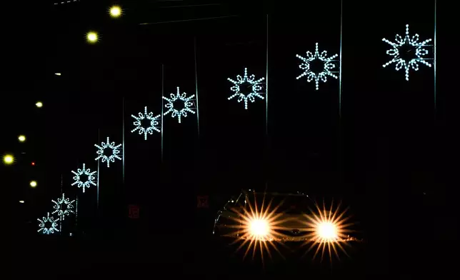 A motorist drives down a street lined with holiday lights, Wednesday, Dec. 10, 2025, in Shawnee, Kan. (AP Photo/Charlie Riedel)
