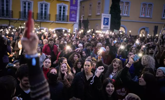 Demonstrators use the light from their cell phones as they gather outside the parliament during a general strike to protest against a new labour package announced by the centre-right government, in Lisbon, Thursday, Dec. 11, 2025. (AP Photo/Armando Franca)
