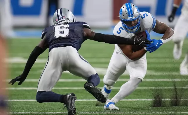 Detroit Lions running back David Montgomery (5) runs after making a catch as Dallas Cowboys safety Donovan Wilson (6) tries to stop him during the second half of an NFL football game Thursday, Dec. 4, 2025, in Detroit. (AP Photo/Paul Sancya)