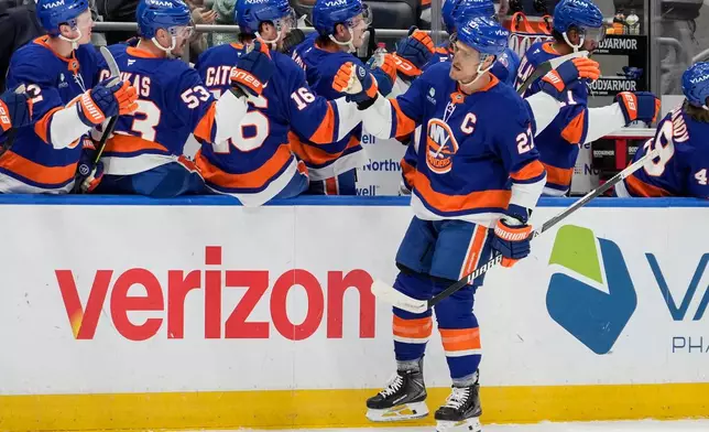 New York Islanders left wing Anders Lee (27) celebrates with teammates after scoring during the first period of an NHL hockey game against Anaheim Ducks, Thursday, Dec. 11, 2025, in Elmont, N.Y. (AP Photo/Yuki Iwamura)