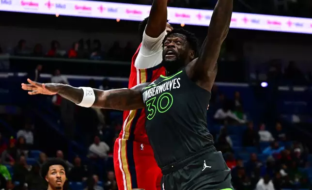 Minnesota Timberwolves forward/center Julius Randle (30) goes up to shoot against New Orleans Pelicans center Derik Queen, second from right, in the first half of an NBA basketball game in New Orleans, Thursday, Dec. 4, 2025. (AP Photo/Ella Hall)