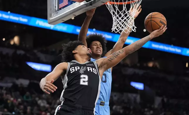 San Antonio Spurs guard Dylan Harper (2) drives to the basket past Memphis Grizzlies forward Jaylen Wells (0) during the second half of an NBA basketball game in San Antonio, Tuesday, Dec. 2, 2025. (AP Photo/Eric Gay)