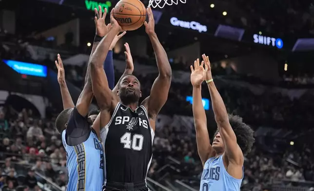 San Antonio Spurs forward Harrison Barnes (40) drives to the basket between Memphis Grizzlies forward Cedric Coward, left, and forward Jaylen Wells (0) during the second half of an NBA basketball game in San Antonio, Tuesday, Dec. 2, 2025. (AP Photo/Eric Gay)