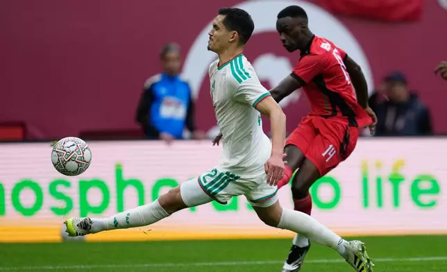 Sudan's Mo Eisa, right, takes a shot at goal next to Algeria's Aïssa Mandi during the Africa Cup of Nations group E soccer match between Algeria and Sudan in Rabat, Morocco, Wednesday, Dec. 24, 2025. (AP Photo/Mosa'ab Elshamy)