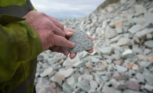 Jim English, Kays Curling Managing Director, shows the amount of the mineral feldspar in a pebble of granite on the island of Ailsa Craig, off the coast of Scotland, Monday, Nov. 10, 2025. (AP Photo/Alastair Grant)