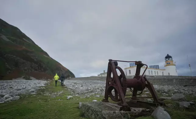 Old quarry equipment rusts, with the lighthouse in the background on Ailsa Craig island, off the coast of Scotland , Monday, Nov. 10, 2025. (AP Photo/Alastair Grant)