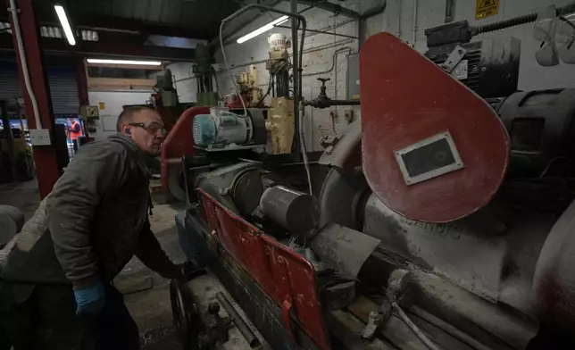 A craftsman uses a stonecutting machine to slice Blue Hone granite blocks which are then used in curling stones at Kays Curling stone factory in Mauchline, Scotland, Tuesday, Nov. 11, 2025. (AP Photo/Alastair Grant)