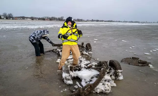 Neil Wakeman, a Luna Pier city council member, holds up a steering wheel as he and friends look over a car that is normally submerged in roughly eight feet of water, about 100 yards off the beach in Luna Pier, Mich., Monday, Dec. 29, 2025. (Andy Morrison/Detroit News via AP)