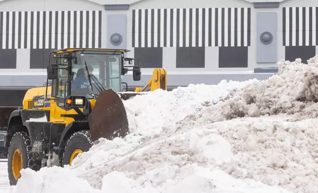 Snow is cleared from a parking lot in Grandville, Mich. on Monday Dec. 29, 2025. (Joel Bissell /MLive.com via AP)