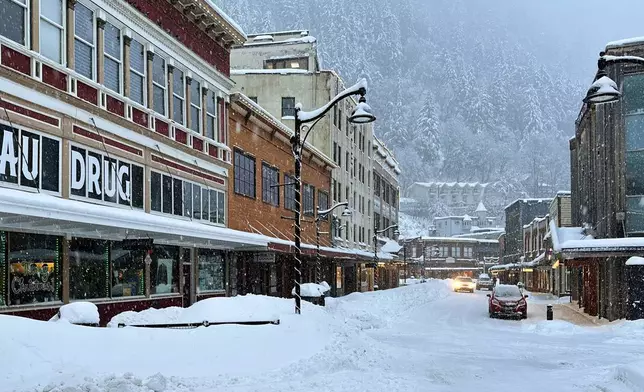 A car drives down a snowy main street in downtown Juneau, Alaska, Monday, Dec. 29, 2025. (AP Photo/Becky Bohrer)