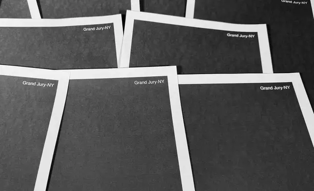 Pages from a totally redacted New York grand jury file into Jeffrey Epstein and Ghislaine Maxwell, released by the U.S. Justice Department, is photographed Friday, Dec. 19, 2025, in Washington. (AP Photo/Jon Elswick)