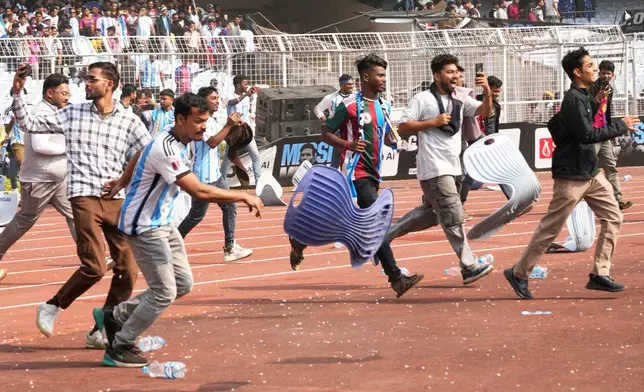 Indian fans vandalize stadium chairs as they run on to the field after failing to get a glimpse of Argentine soccer star Lionel Messi at the Salt Lake Stadium, in Kolkata, India, Saturday, Dec. 13, 2025. (AP Photo/Bikas Das)