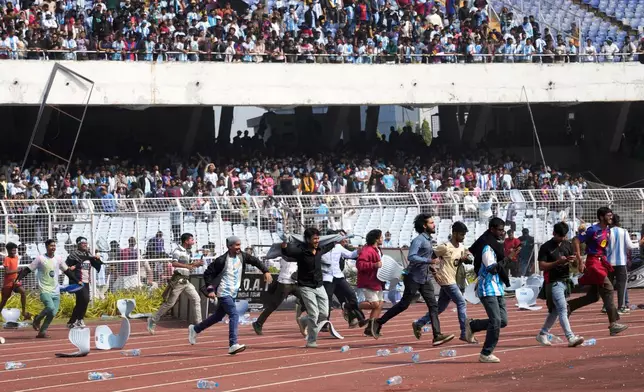 Indian fans vandalize stadium chairs as they run on to the field after failing to get a glimpse of Argentine soccer star Lionel Messi at the Salt Lake Stadium, in Kolkata, India, Saturday, Dec. 13, 2025. (AP Photo/Bikas Das)