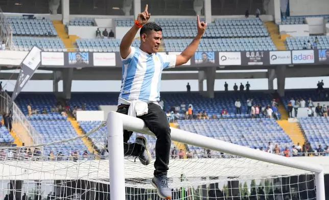 A fan rides a goal post as he protests with others after failing to get a glimpse of Argentine soccer star Lionel Messi at the Salt Lake Stadium, in Kolkata, India, Saturday, Dec. 13, 2025. (AP Photo/Bikas Das)