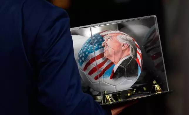 A person carries a soccer ball with a picture of President Donald Trump before the draw for the 2026 soccer World Cup at the Kennedy Center in Washington, Friday, Dec. 5, 2025. (AP Photo/Julia Demaree Nikhinson)