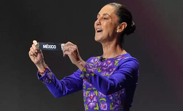 Mexican President Claudia Sheinbaum holds up the team name of Mexico during the draw for the 2026 soccer World Cup at the Kennedy Center in Washington, Friday, Dec. 5, 2025. (AP Photo/Jacquelyn Martin)