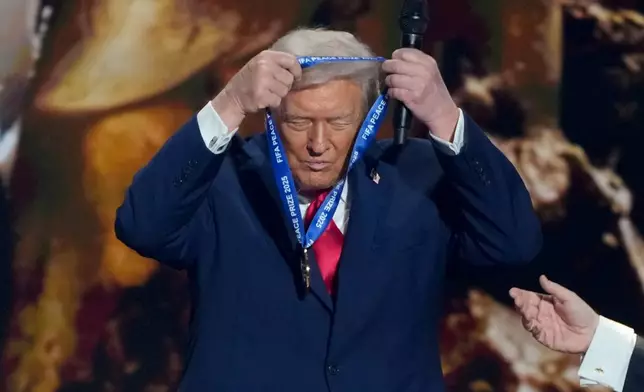 President Donald Trump puts on his FIFA Peace Prize during the draw for the 2026 soccer World Cup at the Kennedy Center in Washington, Friday, Dec. 5, 2025. (AP Photo/Chris Carlson)