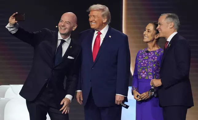 From l-r., FIFA President Gianni Infantino takes a selfie with President Donald Trump, Mexican President Claudia Sheinbaum, and Canadian Prime Minister Mark Carney during the draw for the 2026 soccer World Cup at the Kennedy Center in Washington, Friday, Dec. 5, 2025.(AP Photo/Evan Vucci)