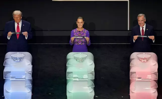 President Donald Trump, Mexican President Claudia Sheinbaum, and Canadian Prime Minister Mark Carney hold their host countries' names up during the draw for the 2026 soccer World Cup at the Kennedy Center in Washington, Friday, Dec. 5, 2025. (AP Photo/Alex Brandon)