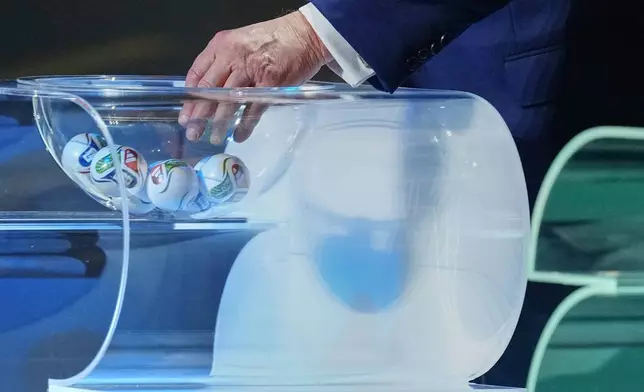 President Donald Trump reaches in a bowl to gather a ball during the draw for the 2026 soccer World Cup at the Kennedy Center in Washington, Friday, Dec. 5, 2025. (Jia Haocheng/Pool Photo via AP)