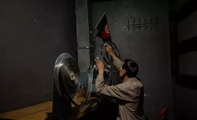 FILE - Rahmatullah Ezati plays back a film reel in the projection room of the historic Ariana Cinema in Kabul, Afghanistan, Nov. 8, 2021, before it was demolished in December 2025 by Taliban authorities to make way for a new shopping center. (AP Photo/Bram Janssen, File)