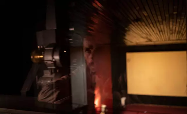 FILE - Rahmatullah Ezati looks out to the theatre from the projection room of the Ariana Cinema in Kabul, Afghanistan, Nov. 8, 2021, before the cinema was demolished in December 2025 by Taliban authorities to make way for a new shopping center. (AP Photo/Bram Janssen, File)