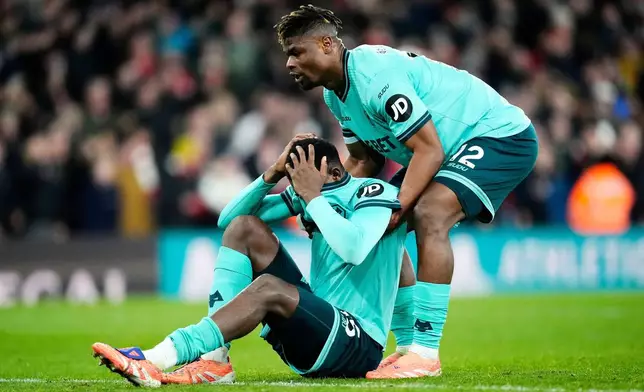 Wolverhampton Wanderers' Yerson Mosquera, left, is picked up by with Emmanuel Agbadou after scoring an own goal during the English Premier League soccer match between Arsenal and Wolves in London, Sunday, Dec. 14, 2025. (Nick Potts/PA via AP)