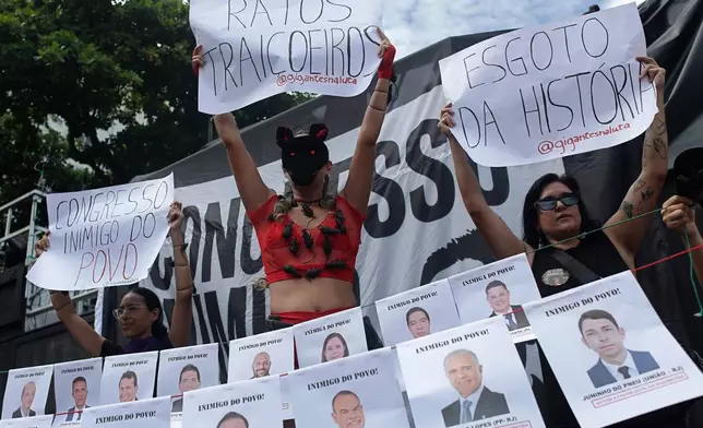 A demonstrator, center, holds up a sign with "Treacherous rats" written in Portuguese, referring to members of Congress, during a protest against a bill that looks to reduce former President Jair Bolsonaro's prison time, in Rio de Janeiro, Sunday, Dec. 14, 2025. (AP Photo/Bruna Prado)