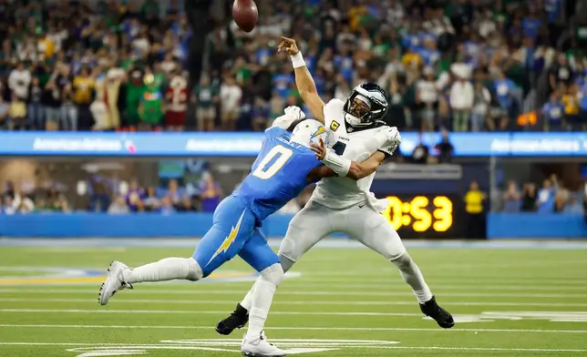 Philadelphia Eagles quarterback Jalen Hurts (1) throws as he is tackled by Los Angeles Chargers linebacker Daiyan Henley (0) during the first half of an NFL football game Monday, Dec. 8, 2025, in Inglewood, Calif. (AP Photo/Caroline Brehman)