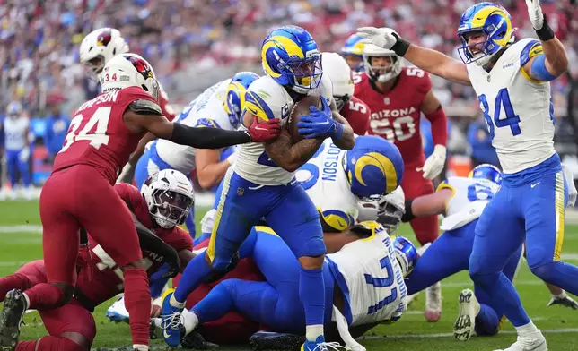 As Los Angeles Rams tight end Colby Parkinson, right, celebrates, Rams running back Kyren Williams, center, bulls past Arizona Cardinals safety Jalen Thompson, left, to score a touchdown in the first half of an NFL football game Sunday, Dec. 7, 2025, in Glendale, Ariz. (AP Photo/Ross D. Franklin)