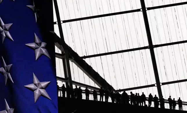 Spectators are silhouetted during the national anthem before an NFL football game between the Atlanta Falcons and the Seattle Seahawks, Sunday, Dec. 7, 2025, in Atlanta. (AP Photo/Brynn Anderson)