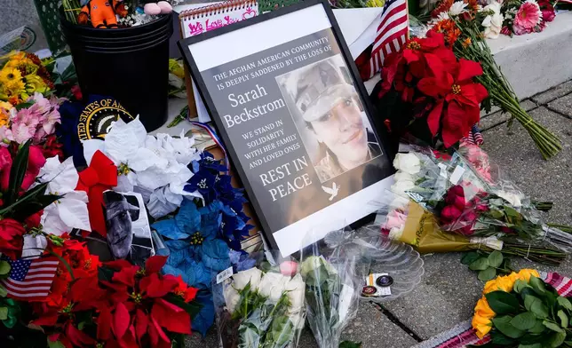 Flowers, challenge coins and other items lay near a photograph of U.S. Army Spc. Sarah Beckstrom at a makeshift memorial outside of Farragut West Station, near the site where two National Guard members were shot, Monday, Dec. 1, 2025, in Washington. (AP Photo/Julia Demaree Nikhinson)