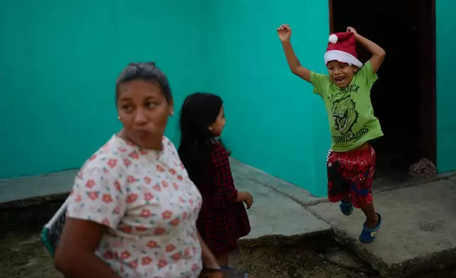 Mathias jumps after receiving a Christmas present from his mother, Mariela Gómez, left, in Maracay, Venezuela, Wednesday, Dec. 24, 2025. The two returned home after abandoning their journey to the United States following President Donald Trump's immigration crackdown. (AP Photo/Matias Delacroix)