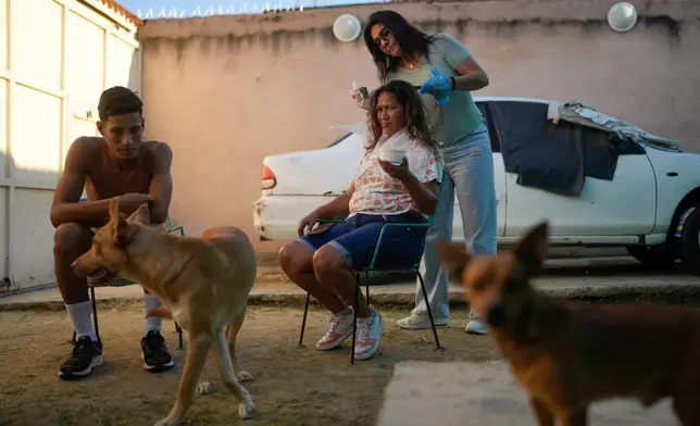 Mariela Gómez, a Venezuelan migrant who abandoned her journey with her children to the United States to return home following President Donald Trump's immigration crackdown, has her hair dyed for Christmas dinner in Maracay, Venezuela, Friday, Dec. 24, 2025. (AP Photo/Matias Delacroix)