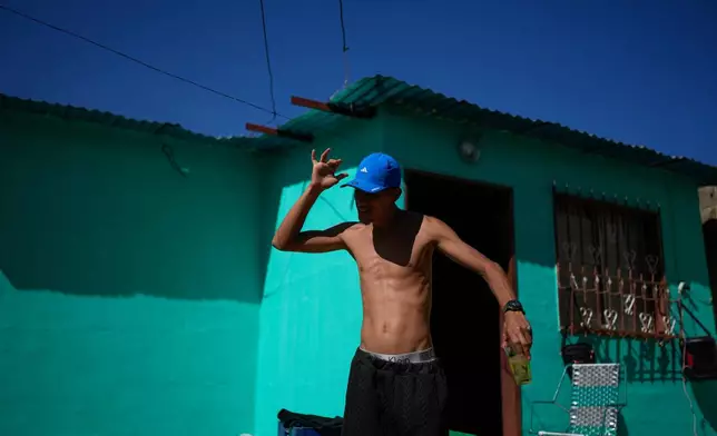 Abraham Castro, a Venezuelan migrant who abandoned the journey with his partner and children to the United States following President Donald Trump's immigration crackdown, dances with a drink in hand during Christmas celebrations in Maracay, Venezuela, Thursday, Dec. 25, 2025. (AP Photo/Matias Delacroix)