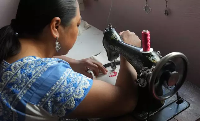 Virginia Veronica Arce Arce, a designer of Nahua folk art embroidery worn by Mexican President Claudia Sheinbaum, works in her workshop at home in the municipality of San Isidro Buen Suceso, Tlaxcala, Mexico, Friday, Dec. 12, 2025. (AP Photo/Marco Ugarte)