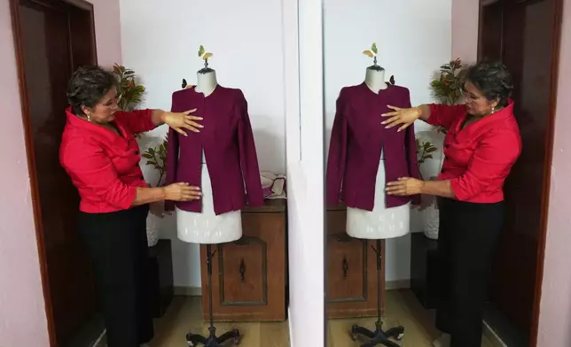 Olivia Trujillo is reflected in a mirror creates an outfit for Mexican President Claudia Sheinbaum at her workshop at home in Mexico City, Thursday, Dec. 11, 2025. (AP Photo/Marco Ugarte)