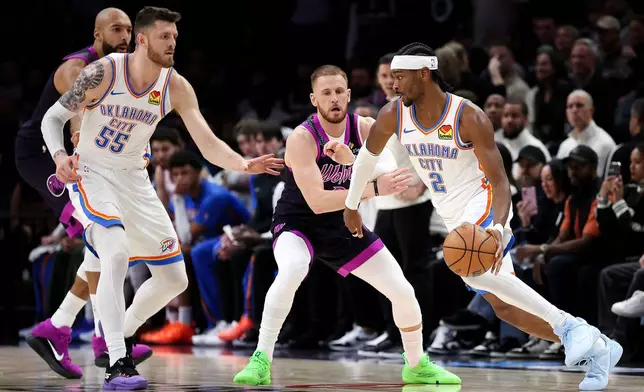 Oklahoma City Thunder guard Shai Gilgeous-Alexander, right, works around Minnesota Timberwolves guard Donte Divincenzo, second from right, during the first half of an NBA basketball game Friday, Dec. 19, 2025, in Minneapolis. (AP Photo/Matt Krohn)
