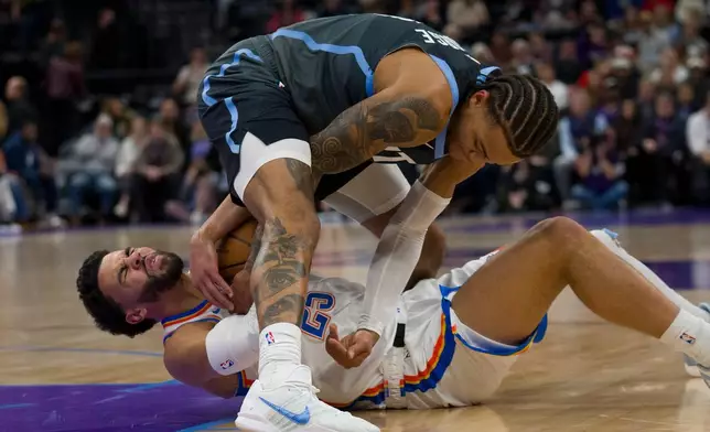 Utah Jazz guard Keyonte George, top, and Oklahoma City Thunder guard Ajay Mitchell (25) fight for the ball during the first half of an NBA basketball game Sunday, Dec. 7, 2025, in Salt Lake City. (AP Photo/Bethany Baker)