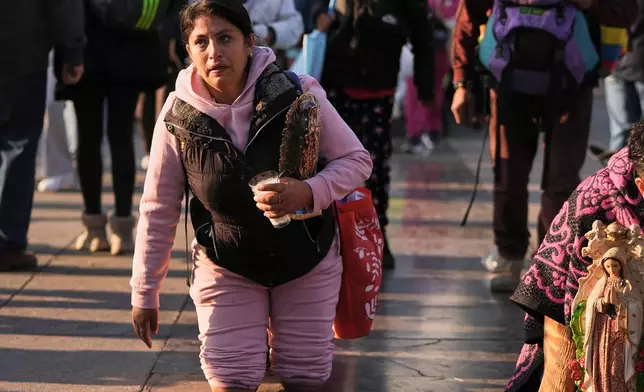A woman crawls on her knees to the Basilica of Our Lady of Guadalupe in Mexico City, on her feast day, Friday, Dec. 12, 2025. (AP Photo/Claudia Rosel)