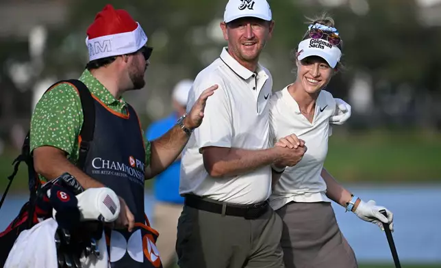 Nelly Korda, right, receives a hug from her father Petr Korda, center, after her shot from the 18th fairway during the final round of the PNC Championship golf tournament, Sunday, Dec. 21, 2025, in Orlando, Fla. (AP Photo/Phelan M. Ebenhack)