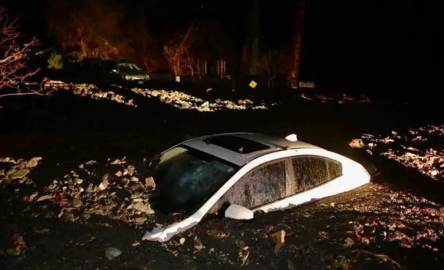 A car sits buried in mud after flooding Wednesday, Dec. 24, 2025, in Wrightwood, Calif. (AP Photo/Wally Skalij)