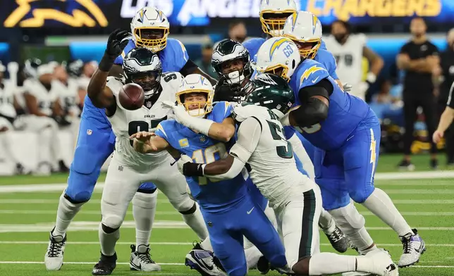 Los Angeles Chargers quarterback Justin Herbert (10) throws as he tackled by Philadelphia Eagles linebacker Jalyx Hunt during the first half of an NFL football game Monday, Dec. 8, 2025, in Inglewood, Calif. (AP Photo/Kevork Djansezian)