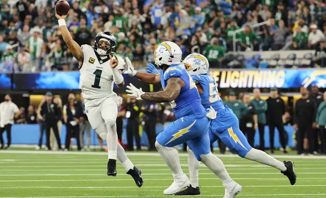 Philadelphia Eagles quarterback Jalen Hurts (1) throws under pressure from Los Angeles Chargers outside linebacker Khalil Mack (52) and linebacker Tuli Tuipulotu (45) during the first half of an NFL football game Monday, Dec. 8, 2025, in Inglewood, Calif. (AP Photo/Kevork Djansezian)