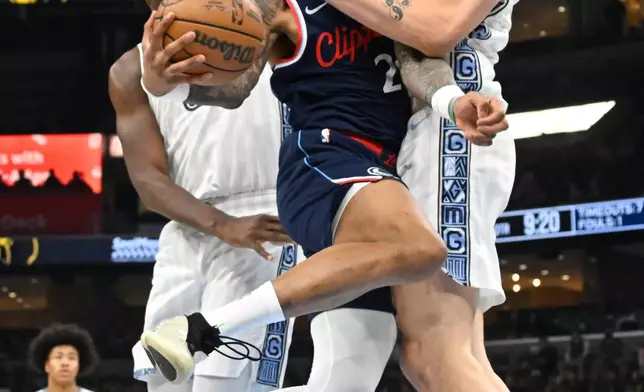 Los Angeles Clippers forward/center John Collins is defended by Memphis Grizzlies center Zach Edey, right, and forward/center Jaren Jackson Jr., left, during the first half of an NBA basketball game Friday, Dec. 5, 2025, in Memphis, Tenn. (AP Photo/John Amis)