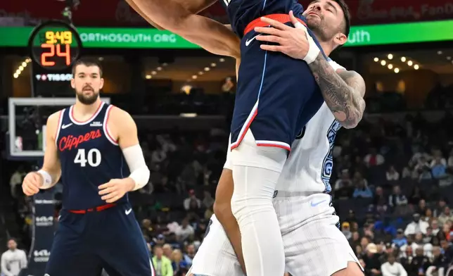 Los Angeles Clippers guard Cam Christie (12) comes up with a rebound as Memphis Grizzlies guard John Konchar defends during the first half of an NBA basketball game Friday, Dec. 5, 2025, in Memphis, Tenn. (AP Photo/John Amis)