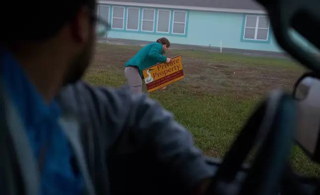 Katie Fernald, Wetland/Rangeland Ecologist with the International Crane Foundation, fixes a private property sign depicting a whooping crane, Friday, Dec. 12, 2025, in Rockport, Texas. (AP Photo/John Locher)