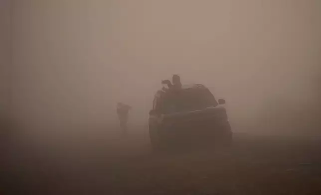 People wait for fog to clear while trying to photograph whooping cranes, Friday, Dec. 12, 2025, in Rockport, Texas. (AP Photo/John Locher)