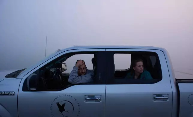 Carter Crouch, Director of Gulf Coast Programs at the International Crane Foundation, left, and Katie Fernald, Wetland/Rangeland Ecologist, International Crane Foundation, wait for fog to clear before launching a boat for whooping crane research, Friday, Dec. 12, 2025, in Rockport, Texas. (AP Photo/John Locher)