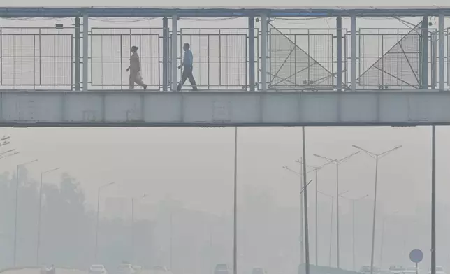 FILE - People walk through an overhead bridge amidst morning smog in New Delhi, India, Oct. 21, 2025. (AP Photo/Manish Swarup, File)